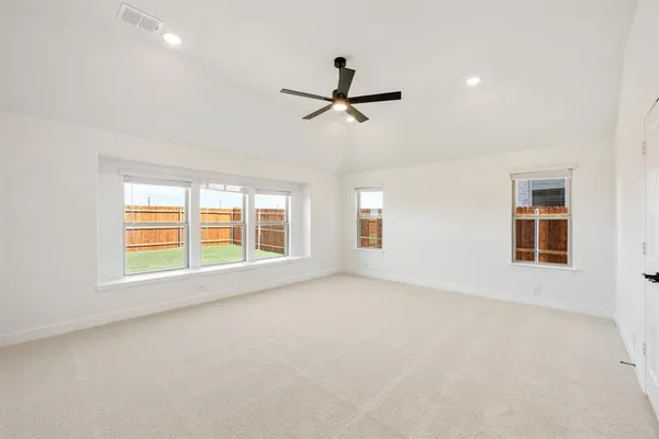 an empty room with windows and fan