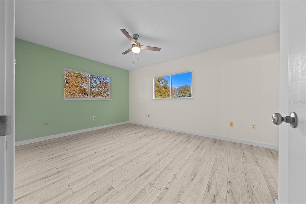 7556 Southwest 112th Lane Ocala, FL 34476 - Photo 18 of 37 a view of an empty room with wooden floor and a ceiling fan