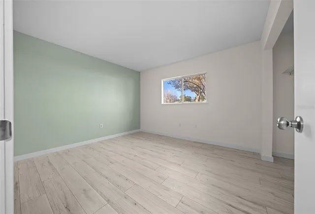 an empty room with wooden floor and windows