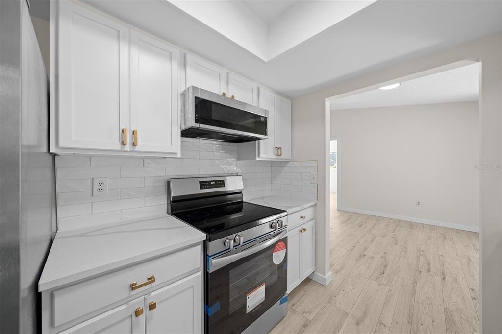 7556 Southwest 112th Lane Ocala, FL 34476 - Photo 8 of 37 a kitchen with stainless steel appliances a stove a microwave and cabinets