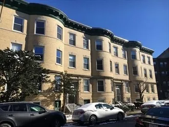 a front view of a building with cars parked
