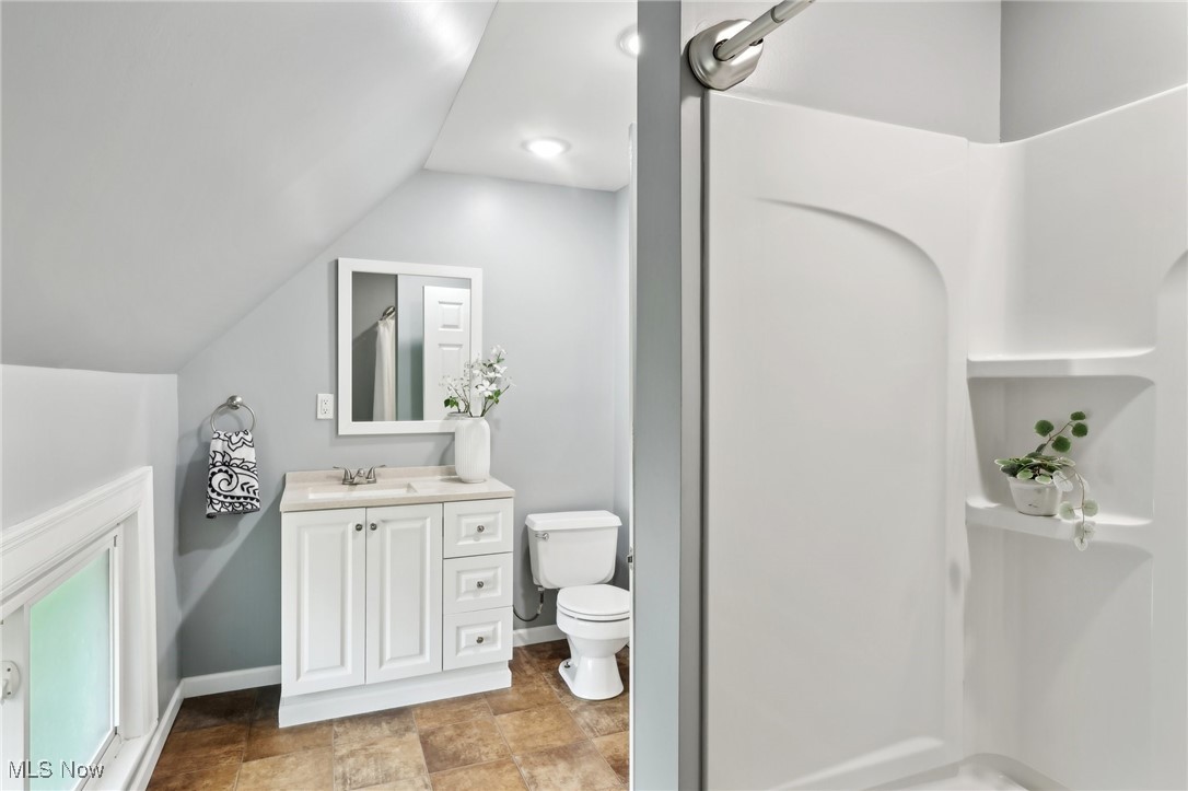 25 Taylor Road Bedford, OH 44146 - Photo 27 of 33 Bathroom with vanity, toilet, a shower, vaulted ceiling, and baseboards