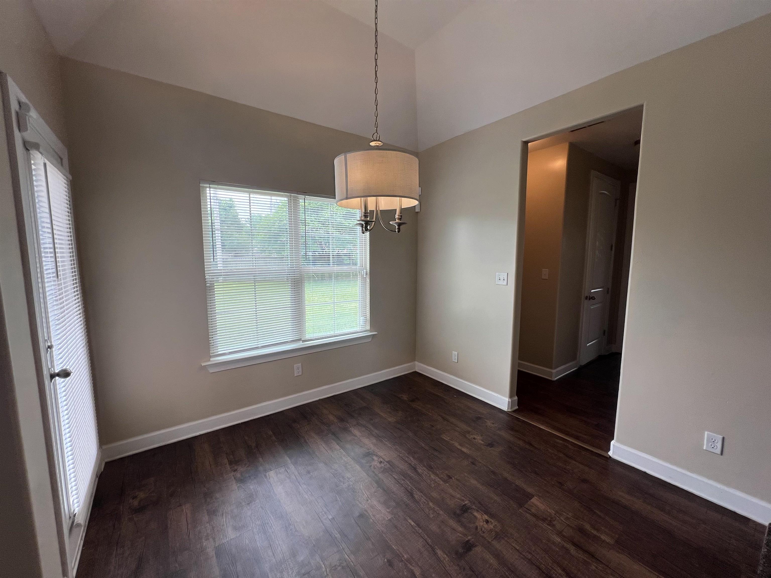 7317 Patsy Circle North Memphis, TN 38125 - Photo 11 of 26 Unfurnished dining area featuring baseboards, dark wood-style flooring, a chandelier, and lofted ceiling