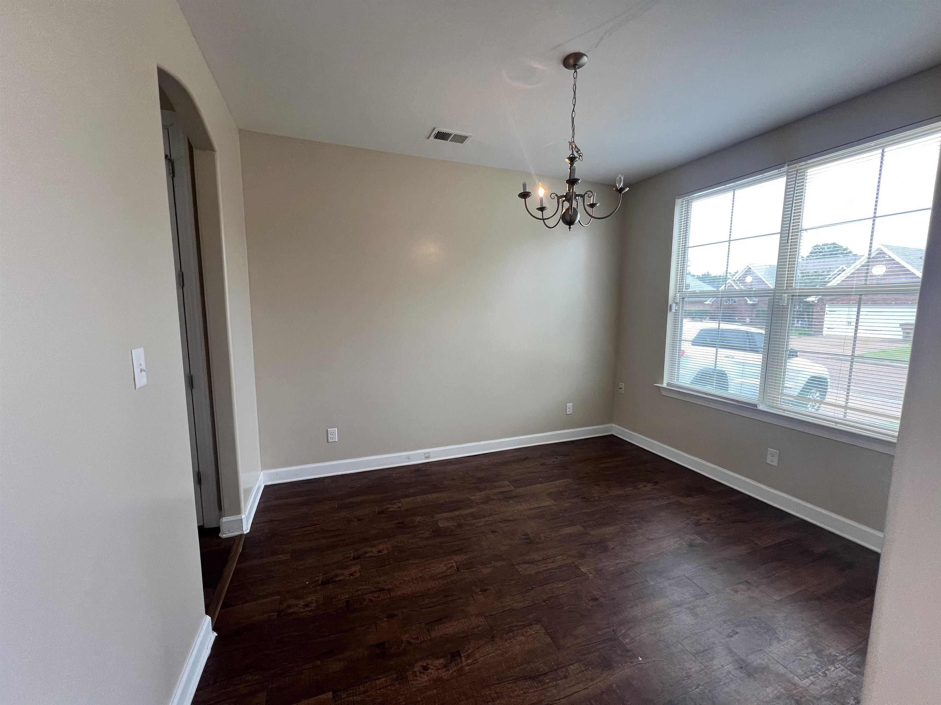 7317 Patsy Circle North Memphis, TN 38125 - Photo 6 of 26 Unfurnished dining area featuring dark wood-style flooring, an inviting chandelier, arched walkways, baseboards, and visible vents