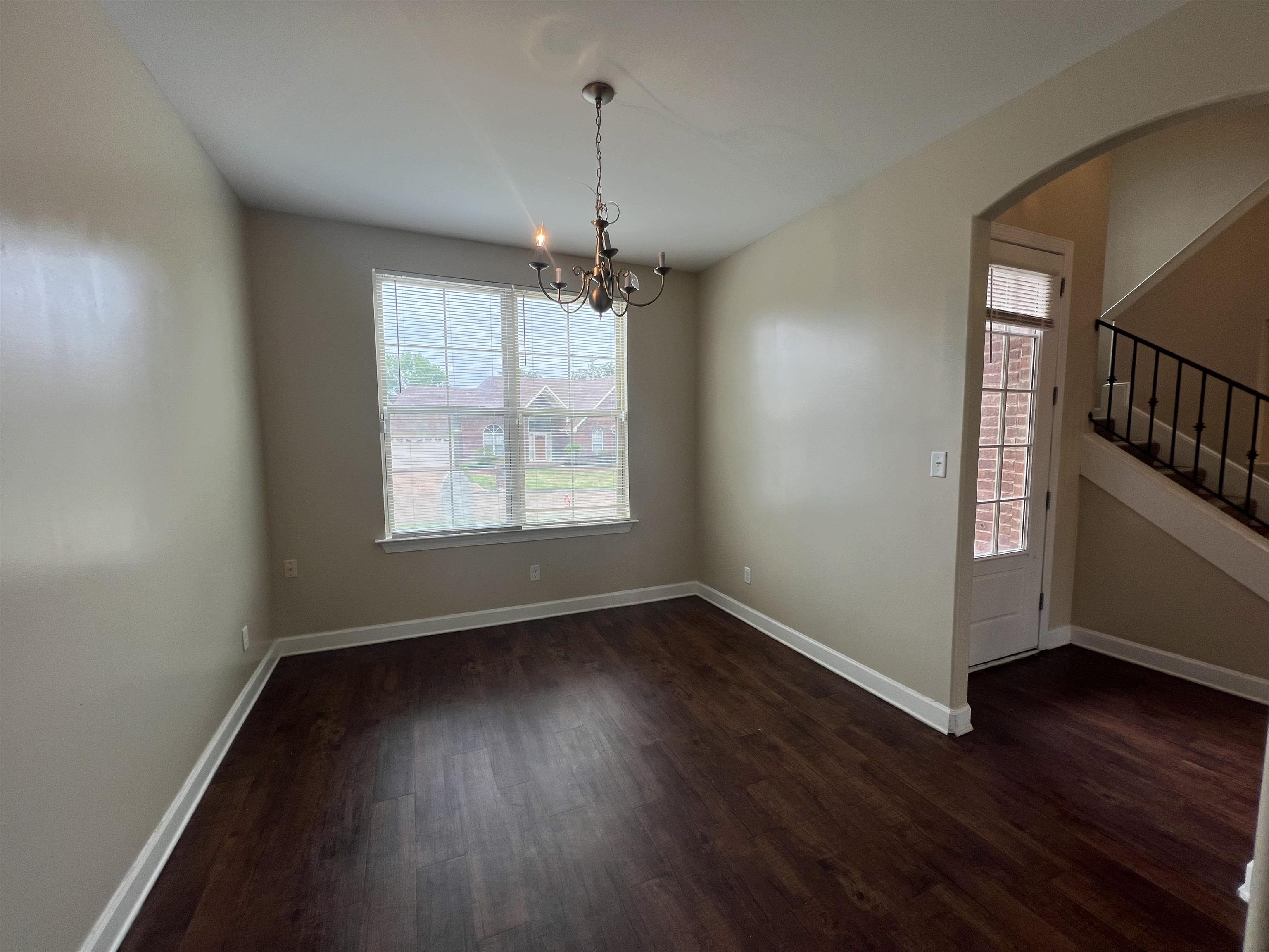 7317 Patsy Circle North Memphis, TN 38125 - Photo 8 of 26 Unfurnished dining area featuring arched walkways, dark wood finished floors, a chandelier, stairs, and baseboards