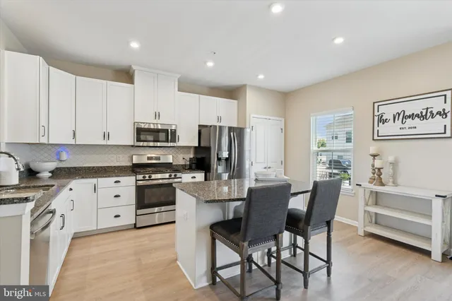 a kitchen with stainless steel appliances kitchen island granite countertop a stove a sink a refrigerator a dining table and chairs