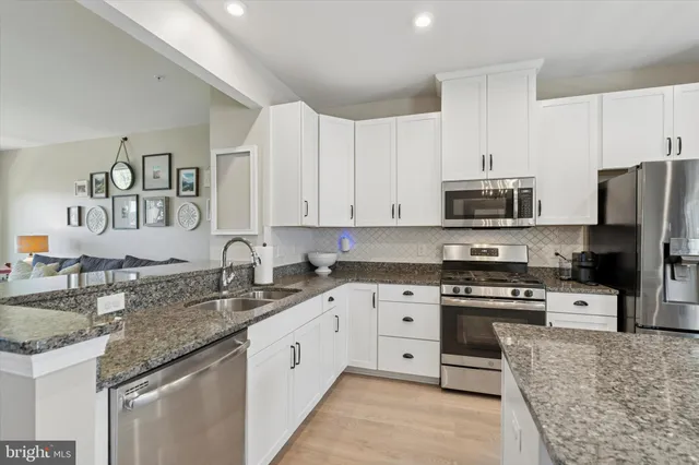 a kitchen with stainless steel appliances granite countertop a sink stove microwave and refrigerator