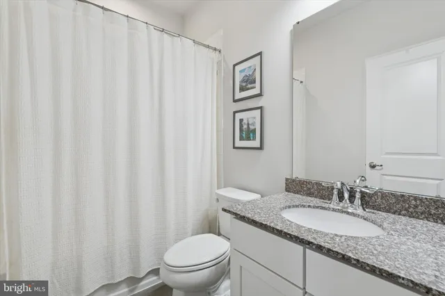 a bathroom with a granite countertop sink and a toilet