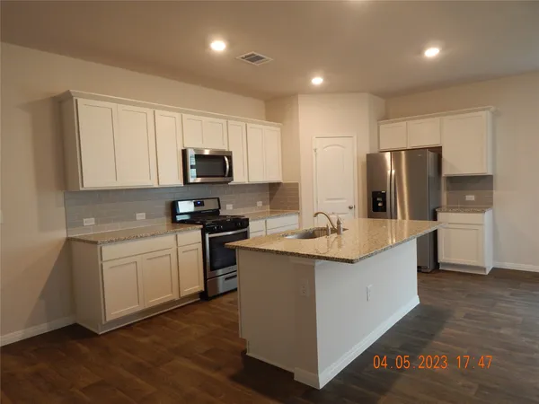 a kitchen with kitchen island granite countertop stainless steel appliances and sink