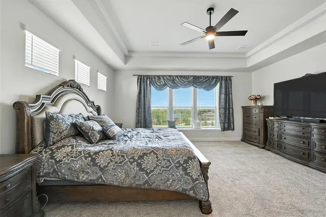 a bedroom with a large bed and a flat tv screen on dresser