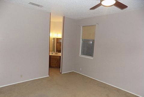 509 Meadowbrook Drive Georgetown, TX 78628 - Photo 16 of 17 A comfortable primary bedroom includes a ceiling fan and a window for natural light, with a peek into the adjacent bath.