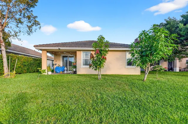 a view of a yard in front of a house with plants and large tree