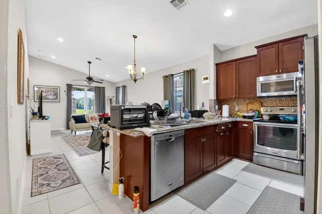 a kitchen with stainless steel appliances granite countertop a stove top oven a sink dishwasher a dining table and chairs with wooden floor