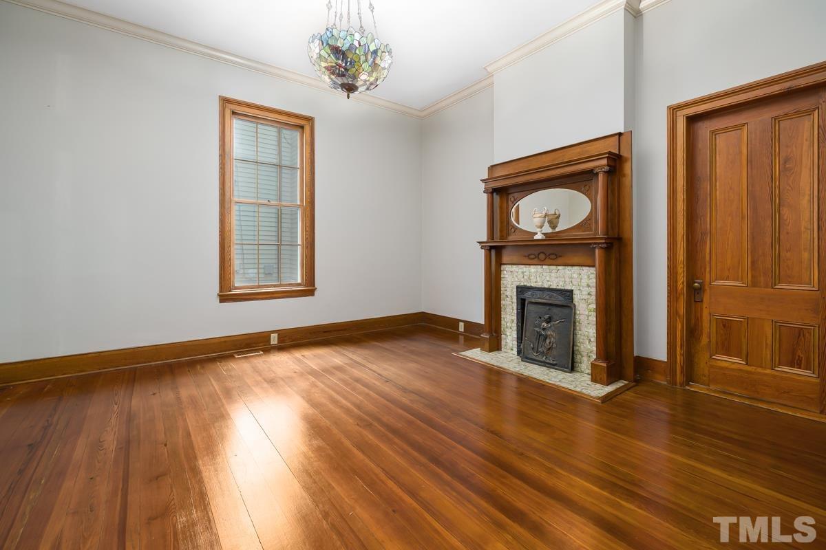 515 Polk Street Raleigh, NC 27604 - Photo 9 of 25 an empty room with wooden floor a fireplace and a window