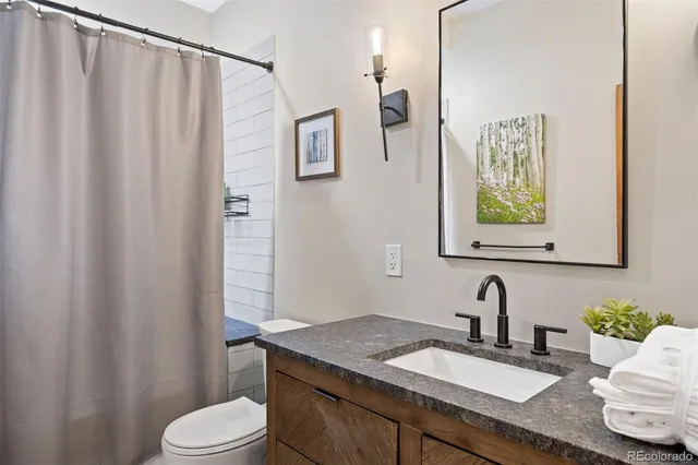 a bathroom with a granite countertop sink vanity mirror and toilet