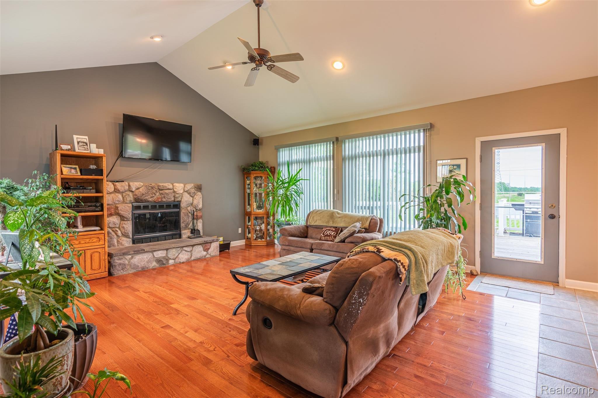 10151 Meskill Road Columbus, MI 48063 - Photo 3 of 39 Living room featuring cathedral ceilings, a natural fireplace, hardwoods throughout, and a walk-out to the expansive back deck.