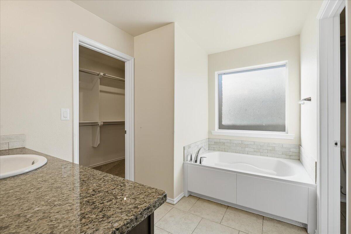 9819 Virginia Avenue Lubbock, TX 79424 - Photo 16 of 29 a bathroom with a granite countertop sink and mirror with bathtub