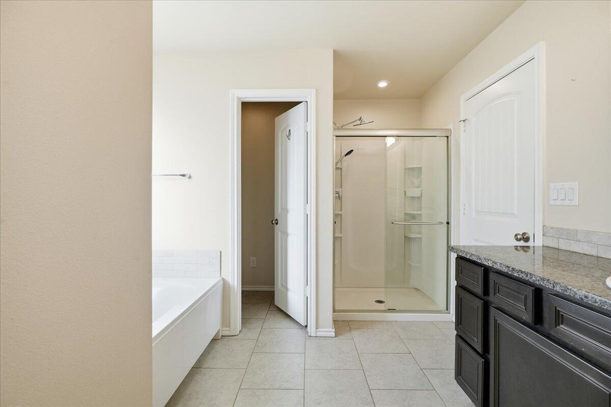9819 Virginia Avenue Lubbock, TX 79424 - Photo 18 of 29 a bathroom with a granite countertop sink a mirror and a bathtub