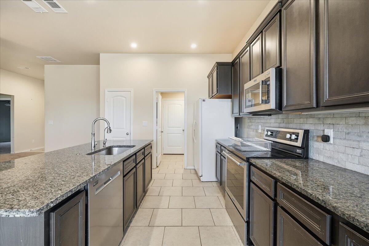 9819 Virginia Avenue Lubbock, TX 79424 - Photo 7 of 29 a kitchen with stainless steel appliances granite countertop a sink stove and refrigerator