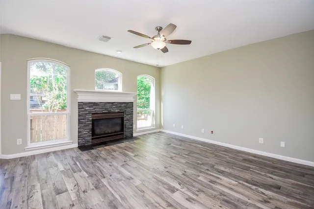 a view of a livingroom with a fireplace a ceiling fan and wooden floor