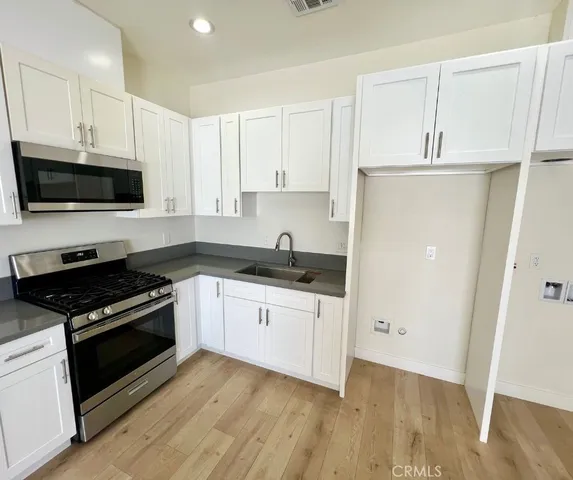 a kitchen with granite countertop a stove a sink and a microwave