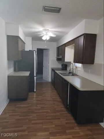 a large kitchen with stainless steel appliances a large counter top a sink a stove and a refrigerator