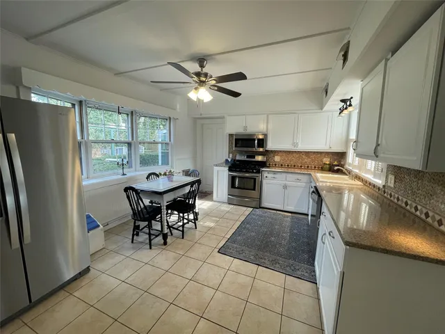 a kitchen with stainless steel appliances granite countertop a stove a refrigerator a sink a dining table and chairs with wooden floor