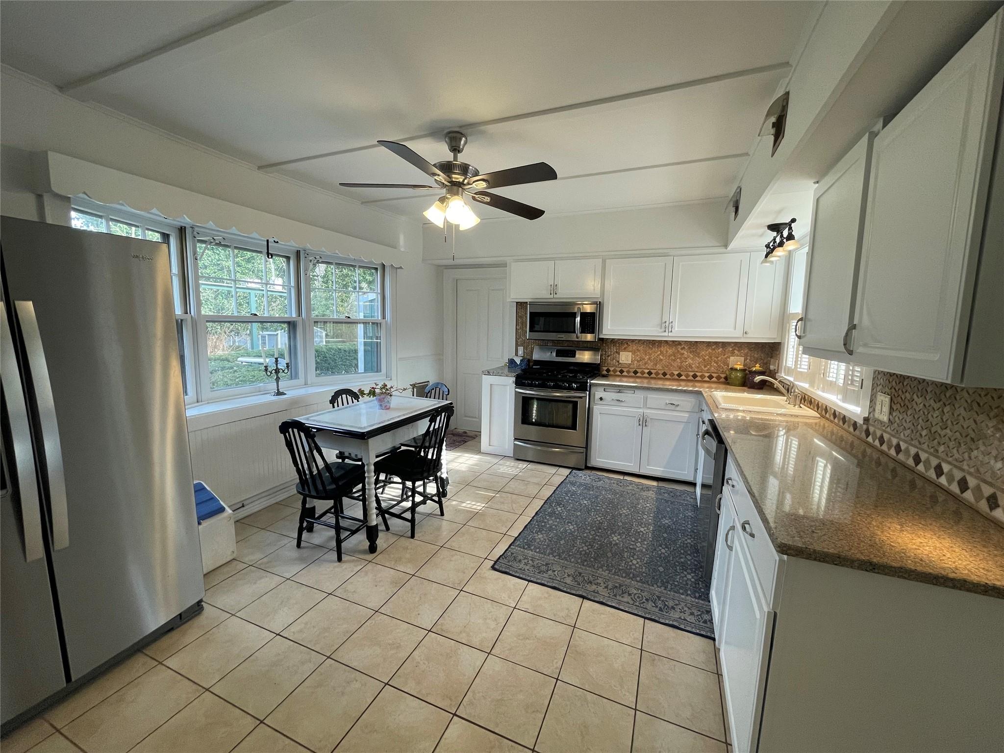 190 South Country Road Remsenburg, NY 11960 - Photo 4 of 20 a kitchen with stainless steel appliances granite countertop a stove a refrigerator a sink a dining table and chairs with wooden floor