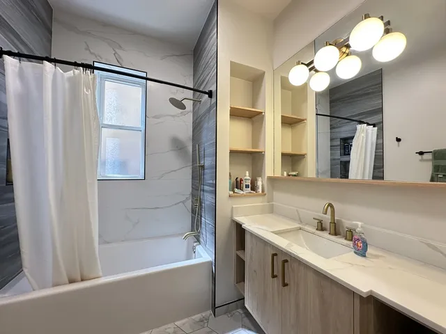 a bathroom with a sink vanity mirror and a bathtub