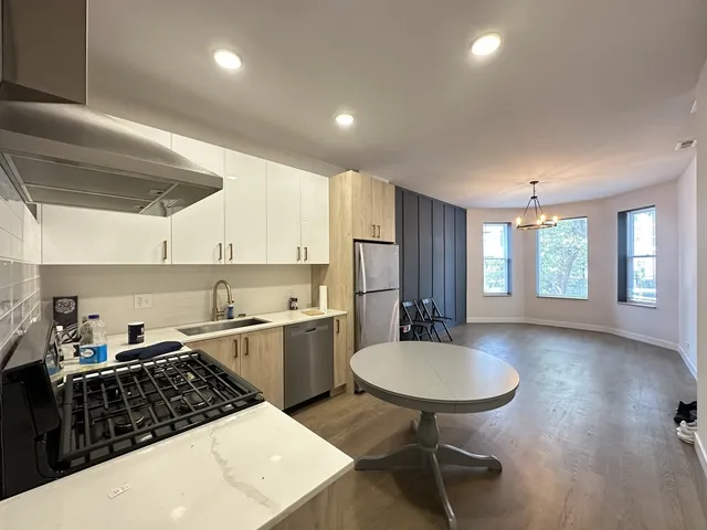 a kitchen with stainless steel appliances granite countertop a sink a stove a refrigerator cabinets and dining table