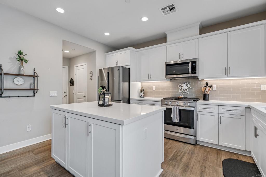 4315 Star Path Way, Unit 4 Oceanside, CA 92056 - Photo 7 of 40 a kitchen with kitchen island white cabinets appliances and sink
