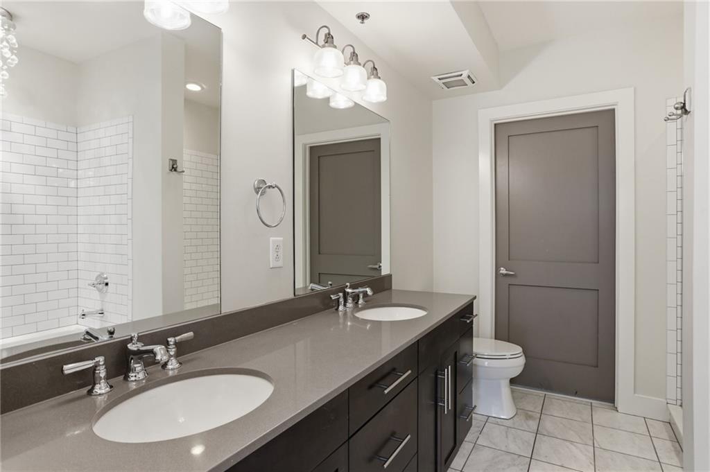1100 Howell Mill Road Northwest, Unit 608 Atlanta, GA 30318 - Photo 17 of 37 a bathroom with a granite countertop sink a toilet a mirror and shower