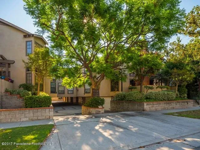a view of a white house next to a yard and a large tree