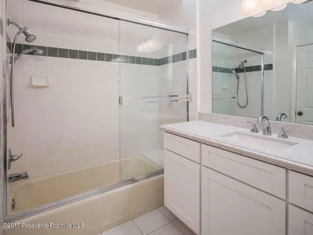 a bathroom with a granite countertop sink a mirror a bathtub and shower