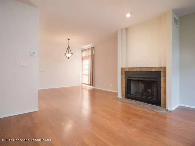 a view of empty room with wooden floor and fireplace