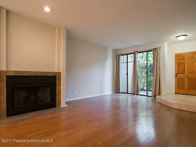 a view of an empty room with glass door and wooden floor