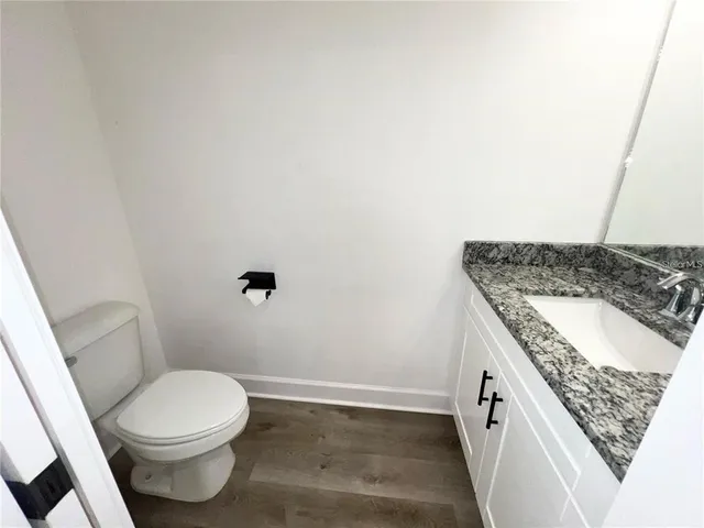 a bathroom with a granite countertop toilet and a sink