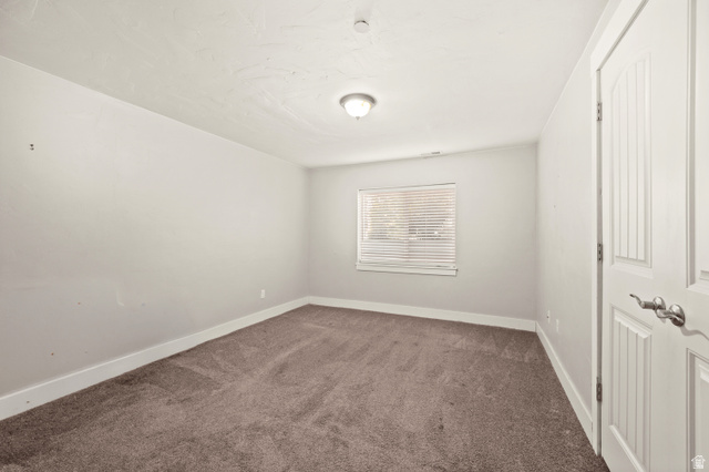 1145 North Christley Lane, Unit 48 Elk Ridge, UT 84651 - Photo 20 of 38 Spacious room featuring neutral-toned walls, plush carpeting, a single window with blinds, a ceiling-mounted light fixture, and a paneled door with brushed nickel hardware