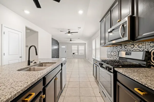 a kitchen with stainless steel appliances granite countertop a sink a stove a refrigerator a washer and a refrigerator