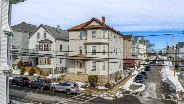 a view of a white house next to a yard with a fountain