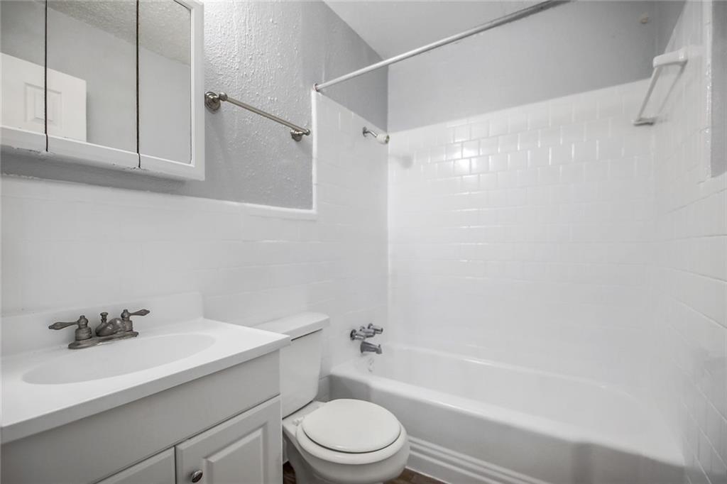 2401 Manor Road, Unit 221 Austin, TX 78722 - Photo 13 of 21 A well-maintained full bathroom featuring classic white subway tile surrounds and a convenient vanity with storage.