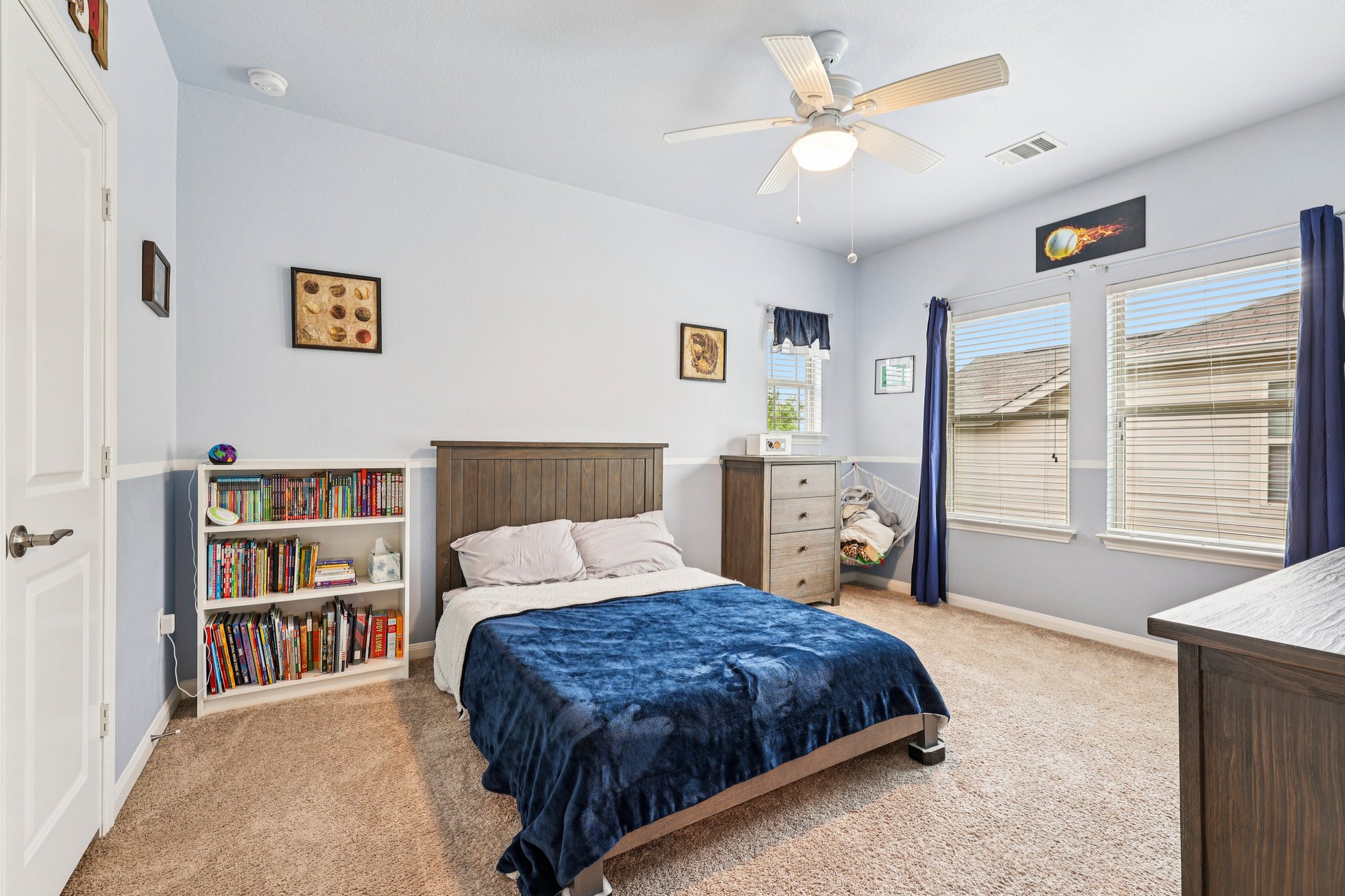 10033 Gertrudis Loop Austin, TX 78747 - Photo 23 of 39 This bedroom features light blue walls, two windows with blinds, and a ceiling fan