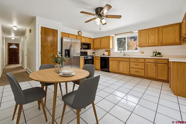 a kitchen with stainless steel appliances granite countertop a sink a stove a dining table and chairs