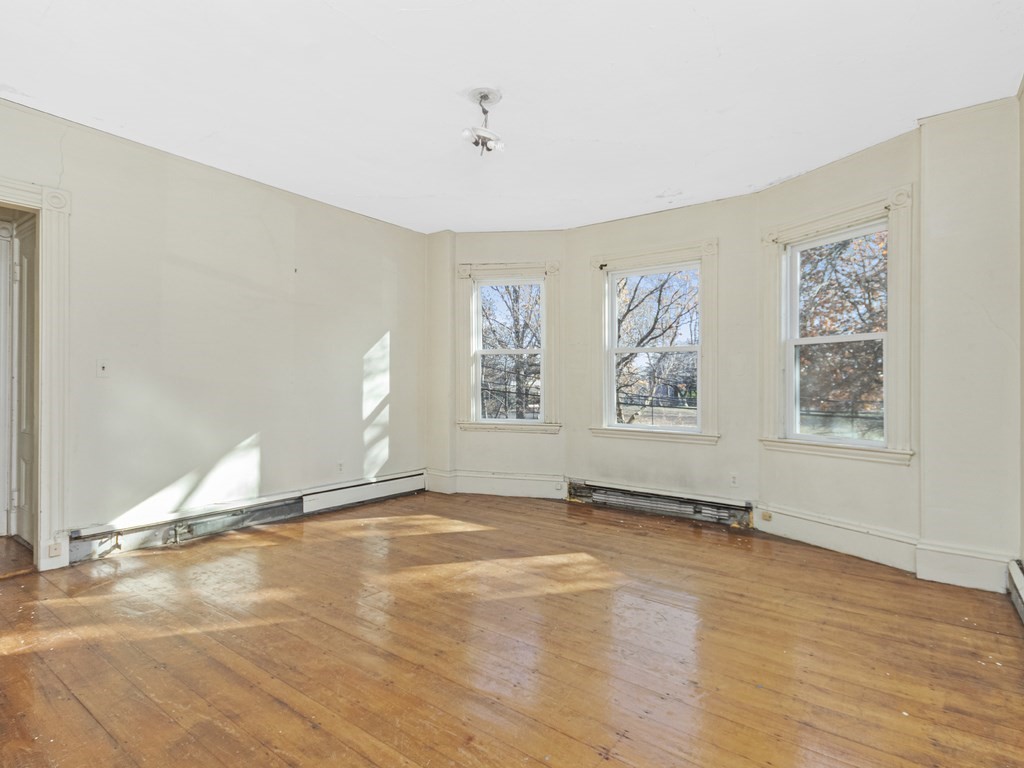 90 Addington Road, Unit 2 Brookline, MA 02445 - Photo 11 of 41 a view of an empty room with a window and wooden floor