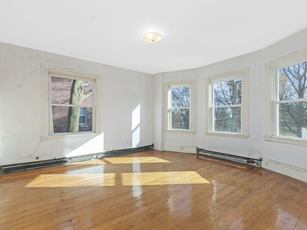 90 Addington Road, Unit 2 Brookline, MA 02445 - Photo 13 of 41 a view of an empty room with window and wooden floor