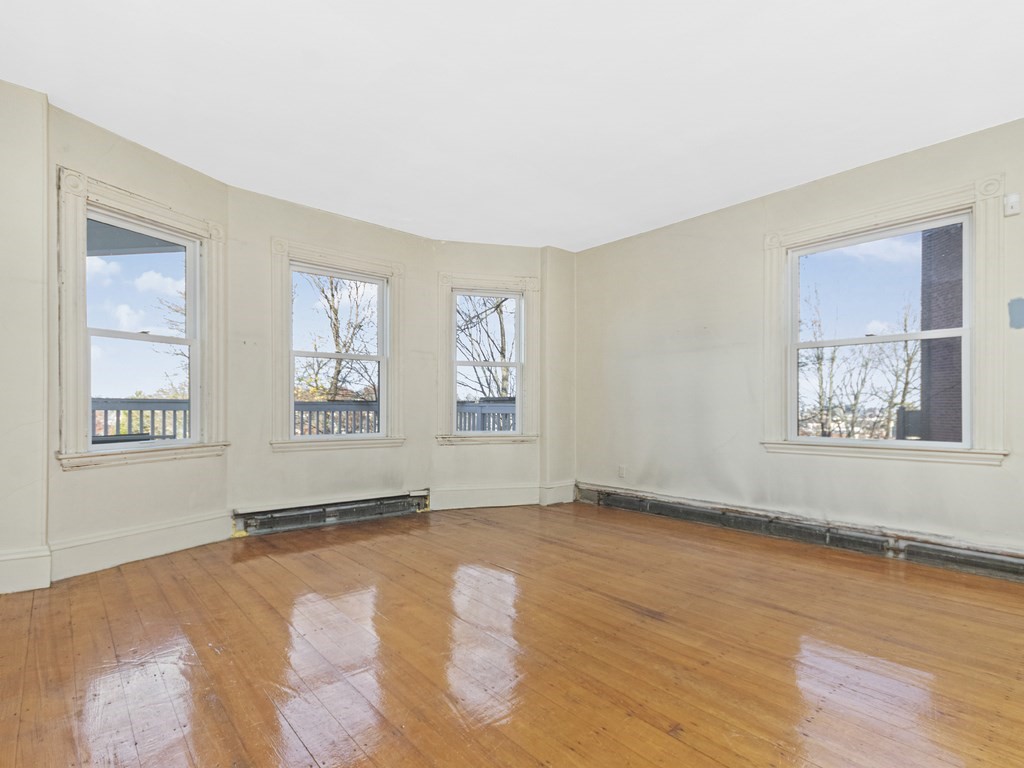 90 Addington Road, Unit 2 Brookline, MA 02445 - Photo 3 of 41 a view of an empty room with window and wooden floor
