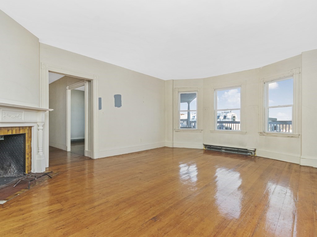 90 Addington Road, Unit 2 Brookline, MA 02445 - Photo 4 of 41 an empty room with wooden floor and a fireplace