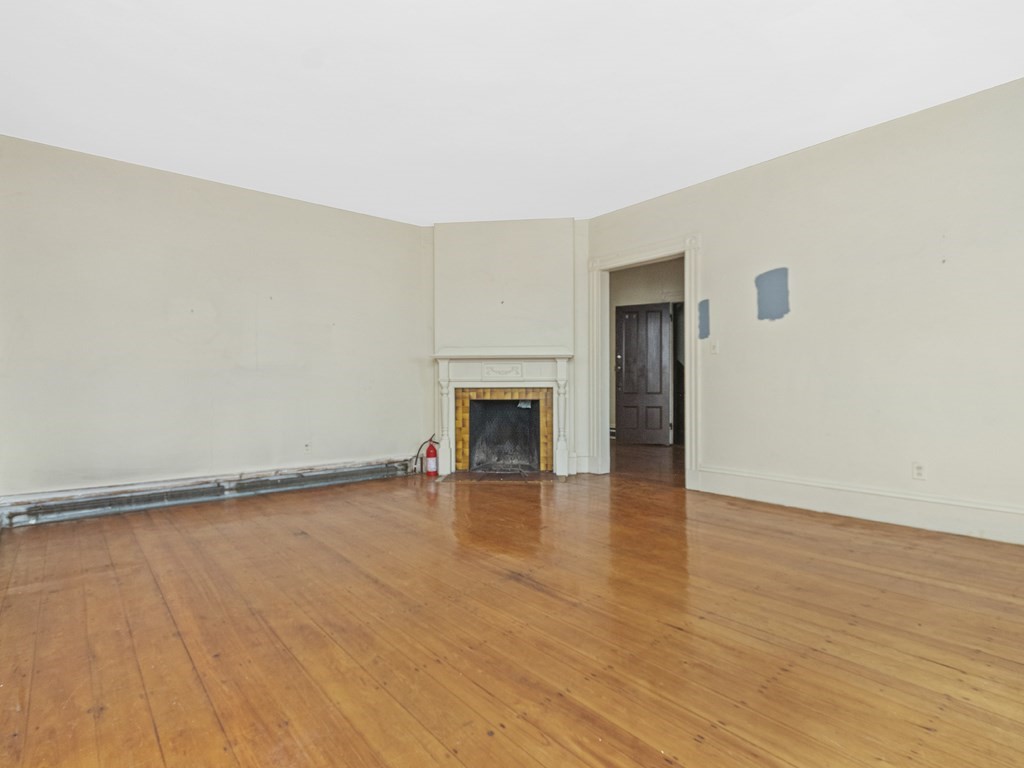 90 Addington Road, Unit 2 Brookline, MA 02445 - Photo 5 of 41 a view of empty room with wooden floor and fireplace