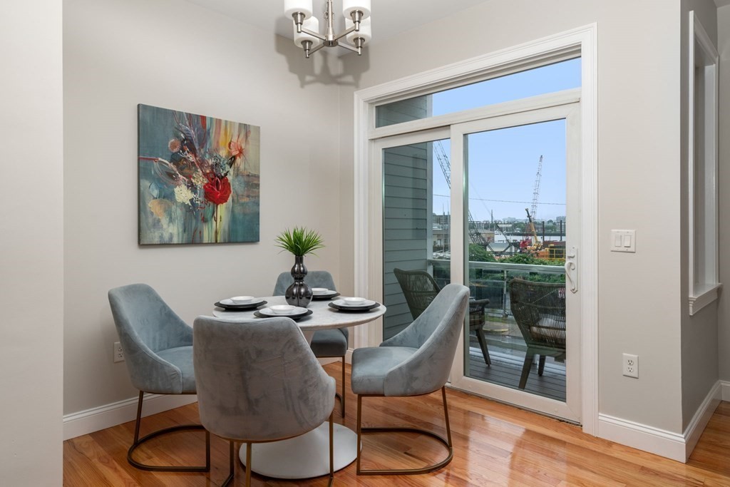 375 Border Street, Unit 375 Boston, MA 02128 - Photo 12 of 34 a dining room with furniture wooden floor a rug a potted plant and a chandelier