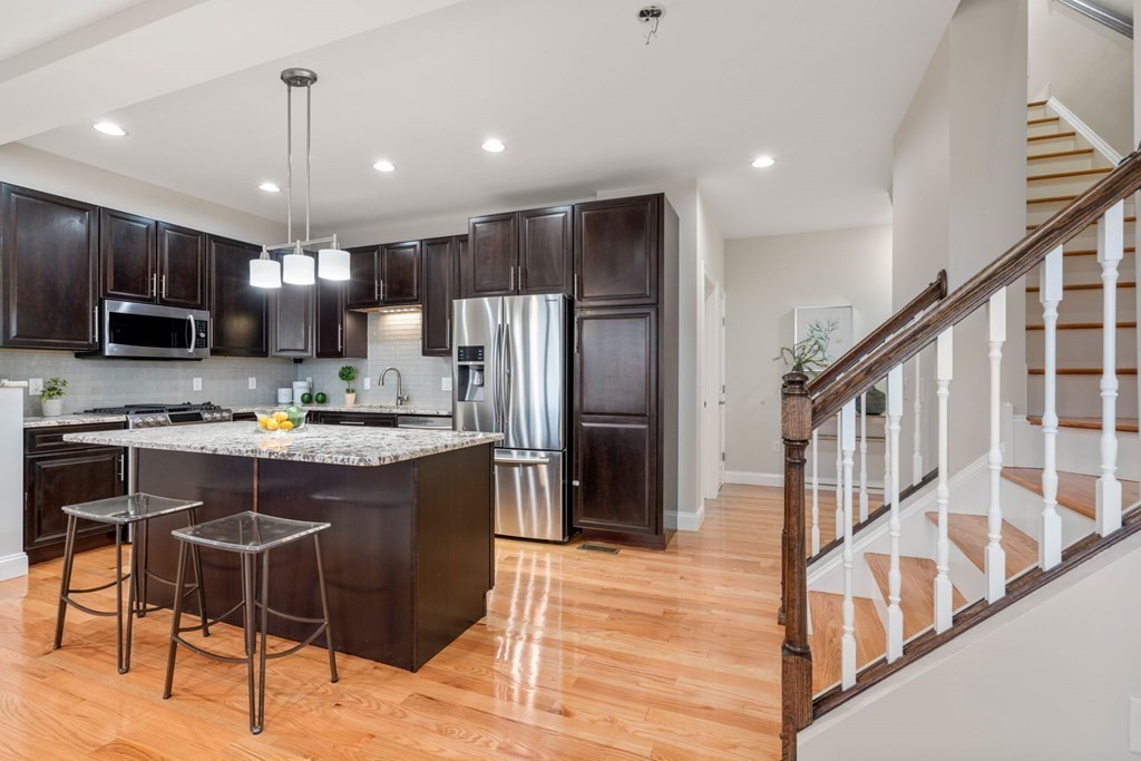 375 Border Street, Unit 375 Boston, MA 02128 - Photo 3 of 34 a kitchen with stainless steel appliances granite countertop a refrigerator a stove a sink a microwave and a dining table with wooden floor
